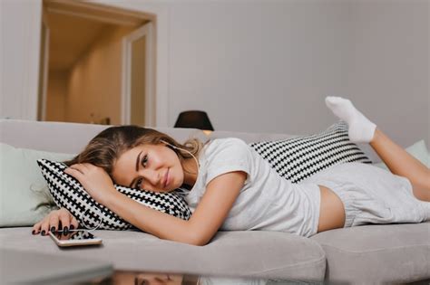 free photo pleased woman in socks lying on cofa with cushions and gently smiling