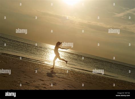 Silhouette Of A Young Girl Running And Doing Handstands In The Sand