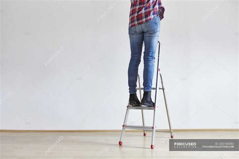 Person Standing On Ladder Leg Jeans Stock Photo