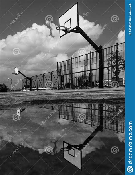 Greyscale Vertical Shot Of A Basketball Court With The Sky S Reflection