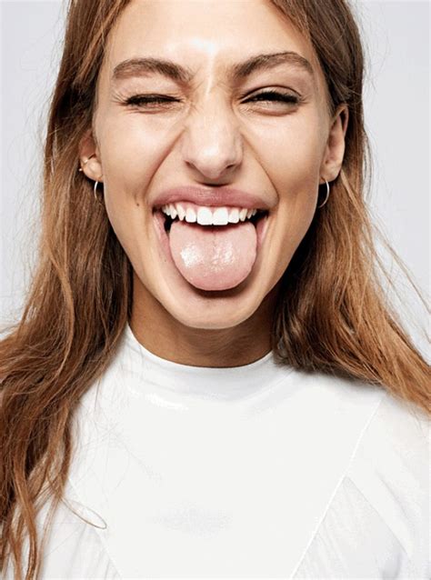a woman sticking her tongue out and making a funny face while wearing a white shirt