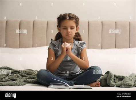 Cute Little Girl Praying Over Bible In Bedroom Stock Photo Alamy