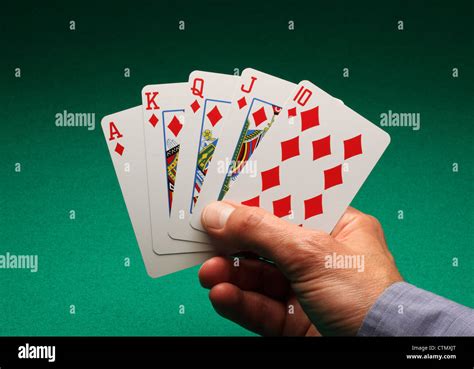 A Mans Hand Holding Playing Cards On A Green Table A Royal Flush Of