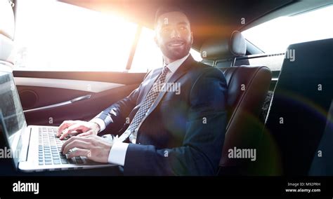 Successful Businessman With Laptop Sitting In The Back Seat Of A