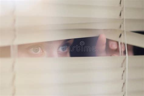 Woman Looking Through The Blinds Waiting For Something Stock Photo