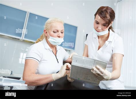 Dentista Y Asistente Dental Leyendo Los Registros Médicos De Un Paciente Antes Del Tratamiento