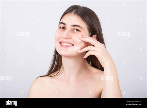 beautiful woman smiling to camera as using softening face cream isolated on white background