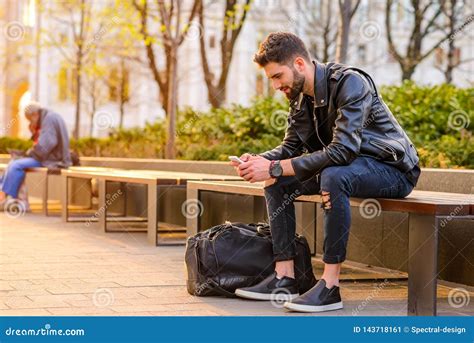 Young Man Sitting On A Bench Stock Image Image Of Jacket Mobile