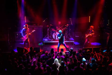 A Group Of People That Are On Stage In Front Of Some Microphones And Lights