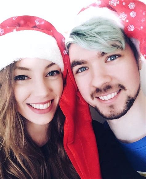 A Man And Woman Are Wearing Santa Hats