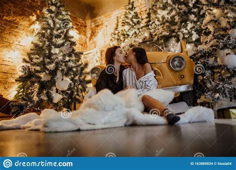 Lesbian Couple Kisses Against Background Of Christmas Decorations And Retro Car Stock Photo