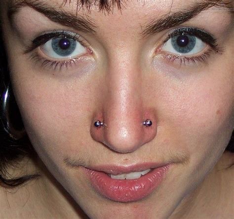 a close up of a person with piercings on her nose and nose ring in front of her face