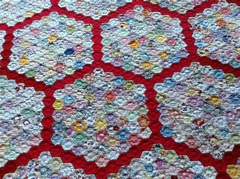 A Close Up Of A Quilt On A Red Table Cloth With White Yellow And Blue