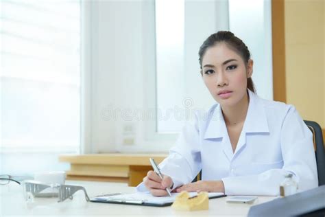 Attractive Young Female Doctor Sitting At Desk In Office Stock Photo