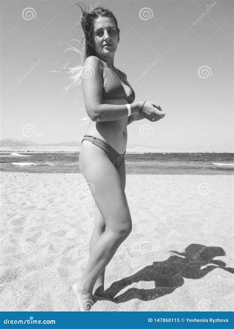 retrato preto e branco da jovem mulher de sorriso com o cabelo longo que levanta contra ondas