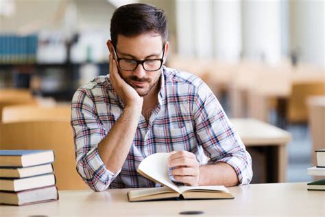 Serious Male Student Reading Book In The College Library Stock Photo
