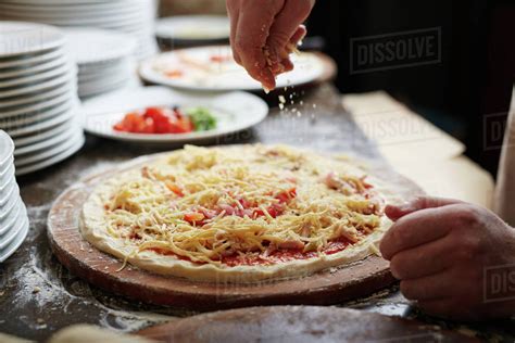 Chef Sprinkling Grated Cheese On Pizza Top Stock Photo Dissolve