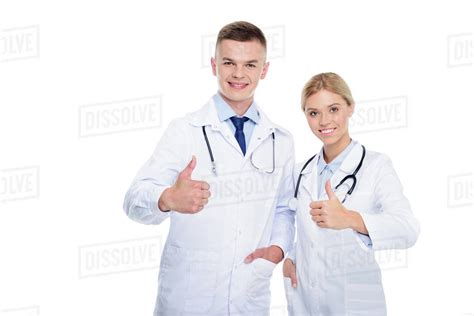 Male And Female Doctors In White Coats With Stethoscopes And Thumbs Up
