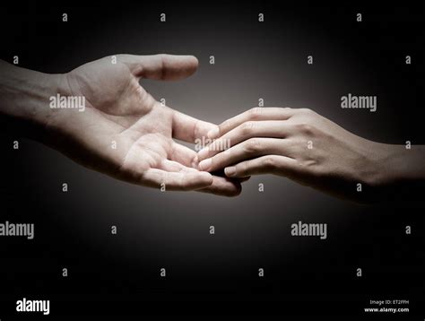two hands are touching each other over black background, concept of ...