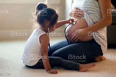 Young Ethnic Daughter Holding Stethescope Up To Moms Pregnant Belly