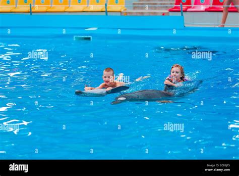 Happy Little Kids Swimming With Dolphins In Dolphinarium Swimming