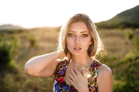 beautiful dreamy blonde girl with blue eyes in a light turquoise dress lying on the stones stock