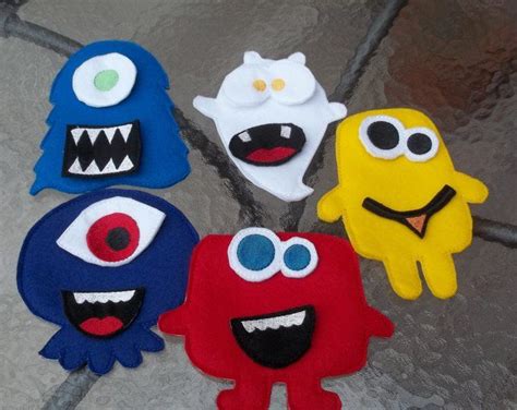 Five Felt Monsters Are Arranged In A Circle On The Floor Each With