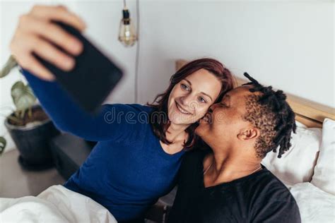 Couples Multiraciaux Prenant Le Selfie Dans Le Lit Image Stock Image Du Téléphone Masculin