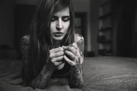 Young Tattooed Woman With Long Hair Lying On The Bed Looking O Stock