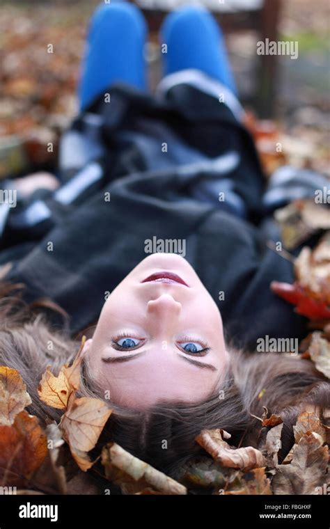Young Teenage Girl Lying Upside Down On A Bed Of Leaves In Autumn Stock