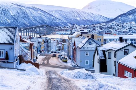 트롬소 노르웨이 겨울 눈 덮인 산에 전통적인 목조 주택이 있는 북극 도시의 전망 프리미엄 사진