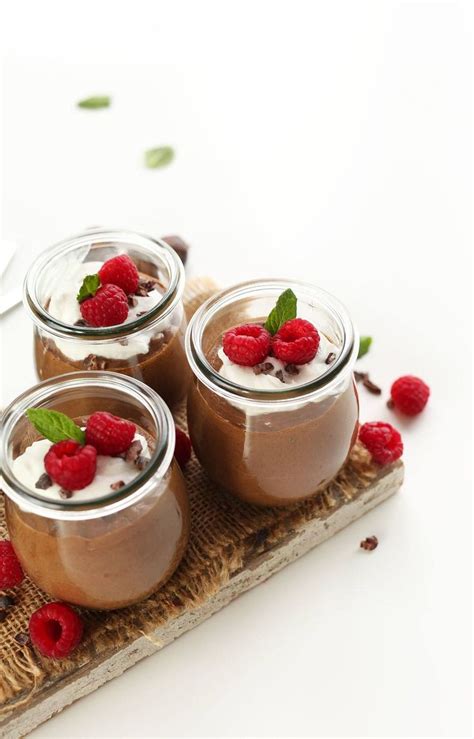 Three Small Jars Filled With Chocolate Pudding And Raspberries On A Wooden Tray Next To A Spoon