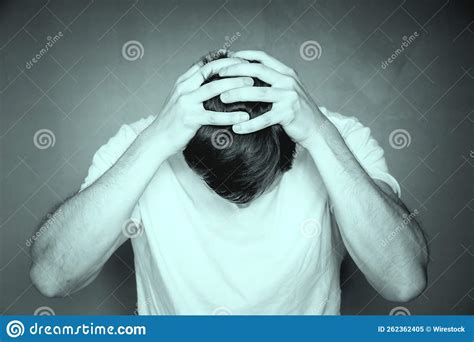 Grayscale Shot Of A Man Holding His Head With His Hands Feeling Distraught And Stressed Stock