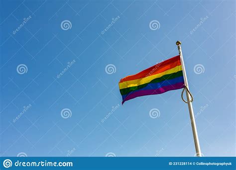close up of a rainbow lgbt flag flying against a bright and clear blue sky suffolk pride stock