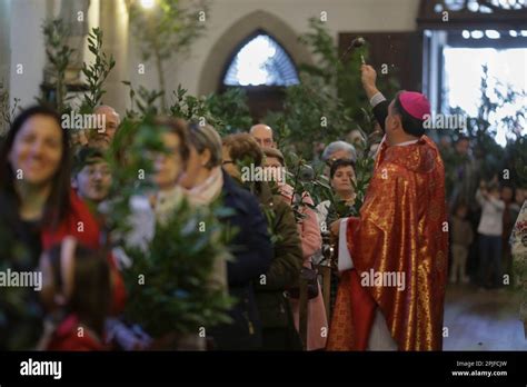A Priest Blesses The Branches Of Parishioners Who Gather During The