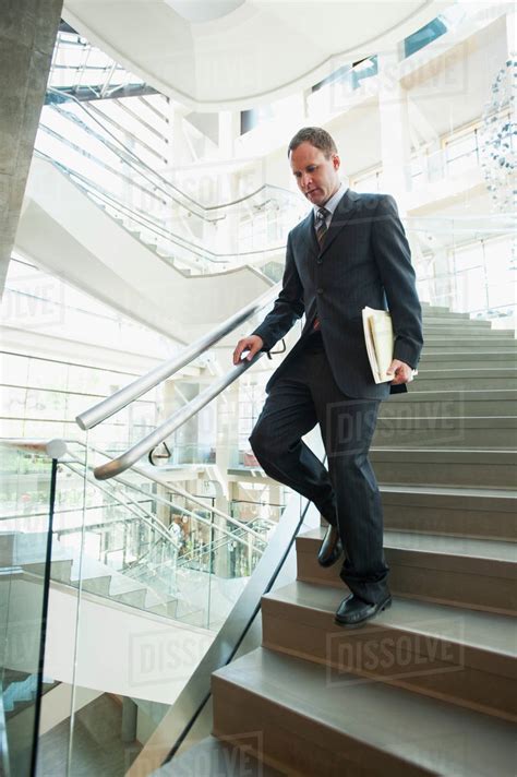 Man Walking Down Stairs In Office Stock Photo Dissolve