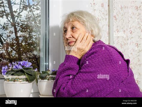 Old Lonely Woman Sitting Near The Window In His House Stock Photo Alamy