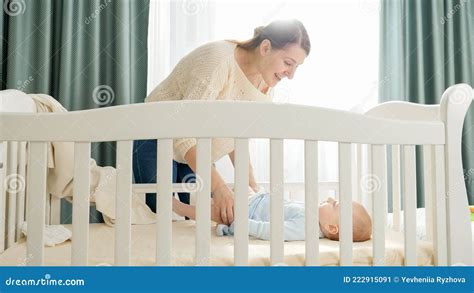 Little Baby Boy Lying In Cradle And Looking At His Smiling Mother