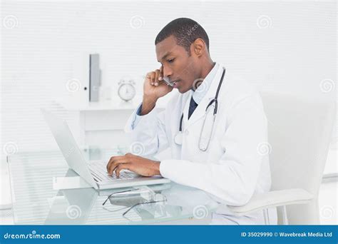 Doctor Using Cellphone And Laptop At Medical Office Stock Photo Image