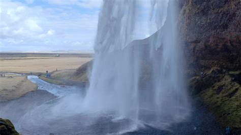 A horizontal shot from behind Seljalandsfoss captures its majestic flow