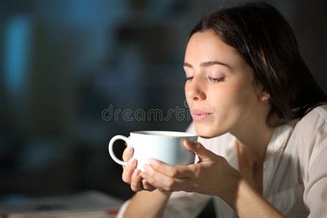 Woman Blowing To Cool Hot Coffee In The Night At Home Stock Photo