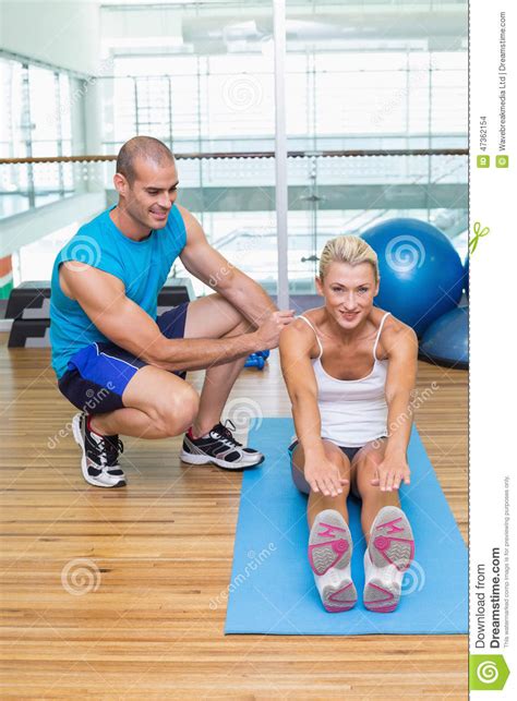 Trainer Assisting Woman With Exercises At Fitness Studio Stock Photo