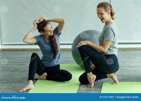 Beautiful Two Women Doing Yoga Practice Together And Talking During A Break In Relax Manner The