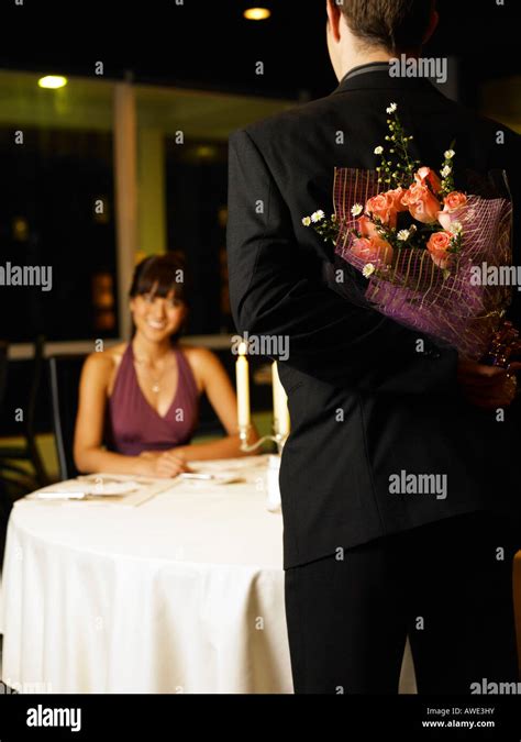 Woman Looking At Man Holding Flowers Behind Back Stock Photo Alamy