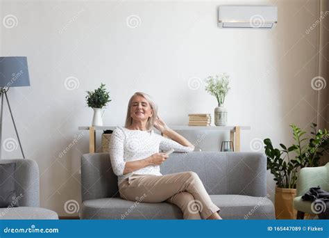 aged woman sitting on couch holding remote control uses airconditioner stock image image of