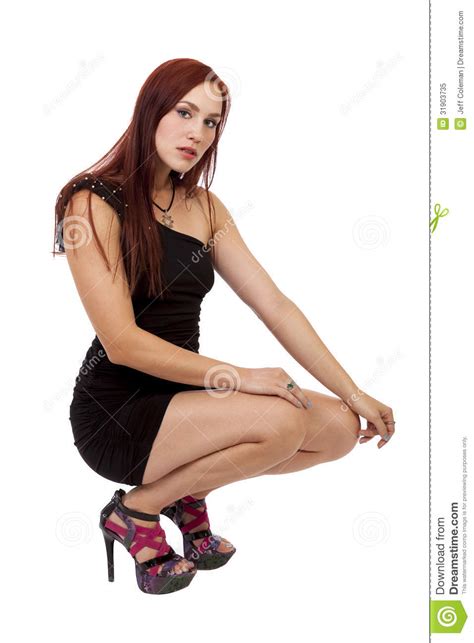 Woman With Red Hair Crouches Down In Her Little Black Dress Stock