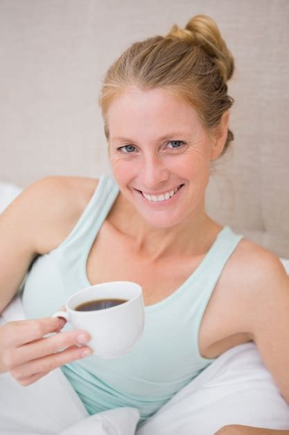 premium photo happy blonde drinking coffee in bed