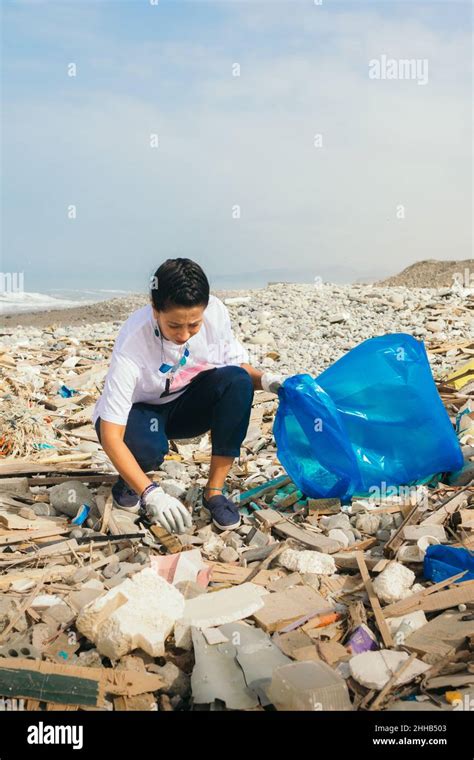 Vertical Image Of A Latin Woman Volunteer Picking Up Trash On A