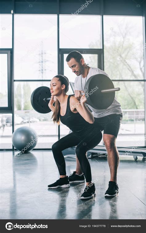Male Personal Trainer Helping Sportswoman Exercises Barbell Gym Stock