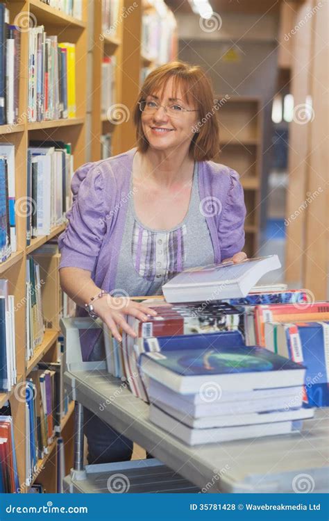 Female Mature Librarian Returning Books In Library Stock Photo Image